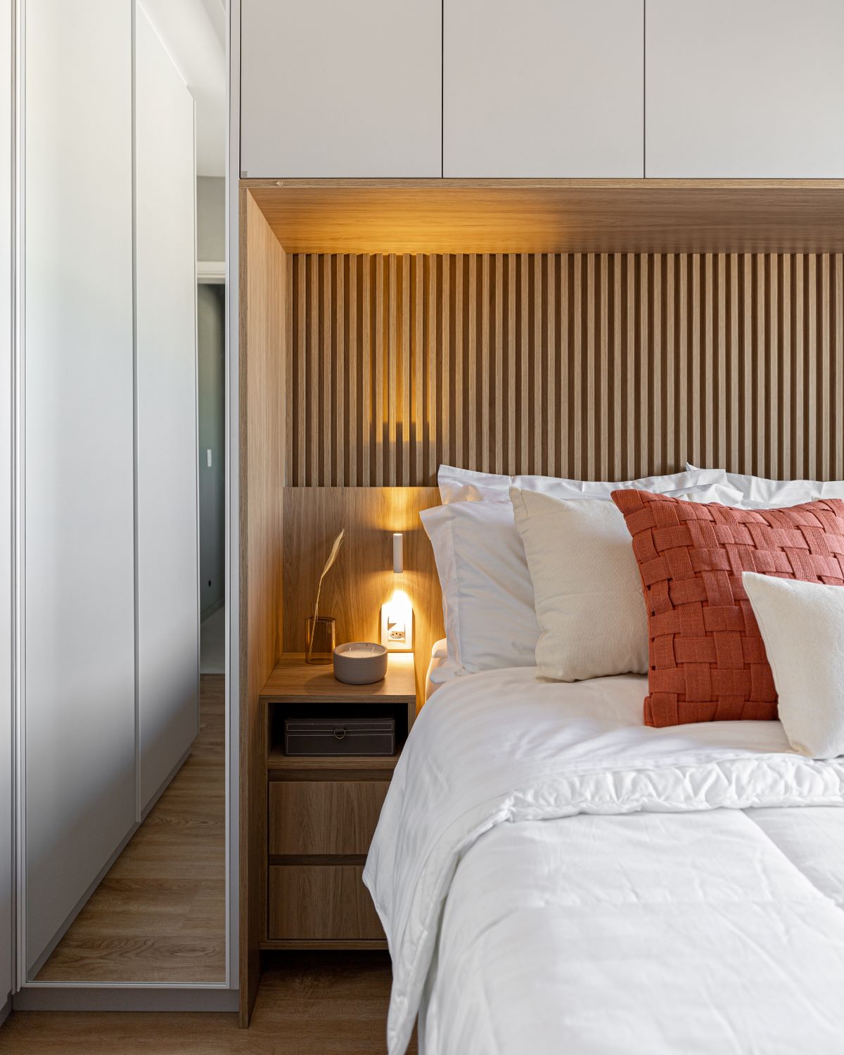 Projeto AB: quarto com cabeceira ripada em madeira, luz indireta e almofadas terracota